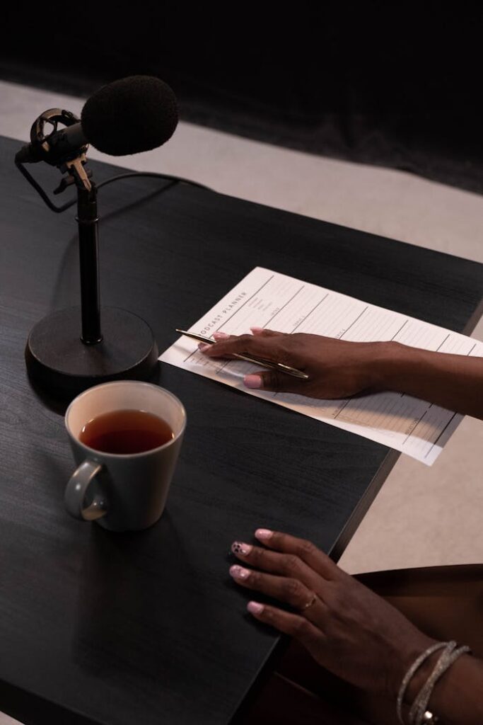 pexels-photo-6878705 A cozy podcast recording setup with tea, notes, and a microphone on a stylish black table.